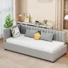 A gray sofa bed with a white mattress and decorative pillows is shown in a room with a window and a shelf. Produktbild-Vorschau