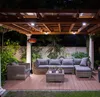An outdoor patio area at night, furnished with a sectional sofa, coffee table, and a patio heater. Produktbild-Vorschau