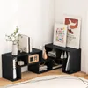 A black modular shelving unit is displayed in a corner of a room, with decorative items and books placed on its shelves. Voir les images du produit