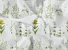 A close-up view of a white fabric with a repeating pattern of green botanical illustrations of plants and flowers. Produktbild-Vorschau