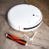 A white robot vacuum cleaner with spare parts on a wooden floor. Produktbild-Vorschau