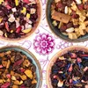 Four bowls of dried tea ingredients arranged in a collage with a decorative floral pattern in the background. Produktbild-Vorschau