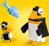 Two LEGO penguins and a LEGO fish on a yellow background. Produktbild-Vorschau