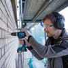 A man is drilling into a brick wall on a construction site. Produktbild-Vorschau