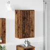 A wooden bathroom cabinet mounted on a white wall, with a wall lamp above it and a small wooden table with bottles below. Náhled obrázku produktu