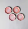 Four pink and orange ceramic plates are arranged on a light gray background. Náhled obrázku produktu