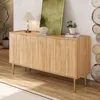 A wooden sideboard with arched doors and gold legs, decorated with a lamp, books, and a plant. Náhled obrázku produktu