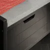 A close-up view of a dark gray storage bench with a gray upholstered seat and a red pillow with white stitching. Anteprima dell’immagine prodotto