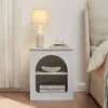 A white bedside table with a lamp, a cup, and books, next to a bed. Podgląd zdjęcia produktu