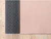 A close-up view of a pink rug with a patterned backing, laid on a wooden floor. Produktbild-Vorschau