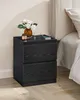 A black wooden nightstand next to a bed. Náhled obrázku produktu