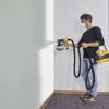 A man is painting a corner of a room with a paint sprayer. Anteprima dell’immagine prodotto