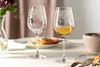 A table setting with two wine glasses, one filled with white wine, and a plate of food. Anteprima dell’immagine prodotto