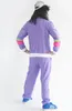 A person wearing a retro tracksuit and a cap, standing with hands on hips. Produktbild-Vorschau