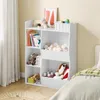 A child's bedroom with a white toy storage shelf filled with books, stuffed animals, and balls, next to a bed with green and white bedding. Produktbild-Vorschau