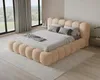 A bedroom scene with a large, plush bed as the focal point, set against large windows with a view of greenery. Voir les images du produit