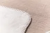 A close-up view of the corner of a soft blanket, showing the stitched edge and the texture of the fabric. Produktbild-Vorschau