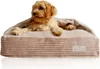 A small, fluffy dog is resting comfortably in a plush, beige dog bed with corduroy-like texture. Produktbild-Vorschau