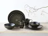 A set of black and gold mandala-patterned stoneware dishes and mugs are arranged on a wooden surface against a white background. Náhľad obrázku produktu