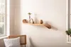 A wooden shelf with decorative items on it, placed on a wall next to a window and a chair. Voir les images du produit