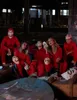 A group of people in red jumpsuits and masks, sitting in an abandoned industrial setting with money scattered around. Náhled obrázku produktu