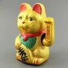A golden Maneki Neko cat figurine with red and green accents, set against a plain gray background. Produktbild-Vorschau