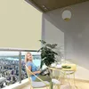 A woman sits on a balcony with a city view, reading a magazine while enjoying a drink. Voir les images du produit
