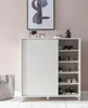 A white shoe cabinet with a sliding door, filled with shoes, is placed against a light pink wall. Náhled obrázku produktu