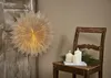 A paper star lantern hangs on a wooden door next to a rustic chair with candles and pine branches. Podgląd zdjęcia produktu