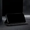 A black flip-style phone case is displayed on a dark surface, with the phone inside and its screen facing the viewer. The background is dark and out of focus. Produktbild-Vorschau