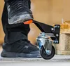 A person's foot is pressing down on a black caster wheel mechanism attached to a wooden pallet. Anteprima dell’immagine prodotto