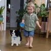 A young child is walking indoors with a toy dog on a leash. Anteprima dell’immagine prodotto
