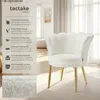 A white, fluffy armchair with gold legs is shown in a well-lit room with sheer curtains in the background. A text overlay on the left side of the image describes the product's features. Produktbild-Vorschau