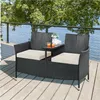 A black rattan loveseat with beige cushions and a small table sits on a wooden deck next to a body of water. Produktbild-Vorschau