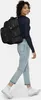 A woman wearing a backpack and jeans, walking. Anteprima dell’immagine prodotto