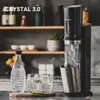 A SodaStream Crystal 3.0 water carbonator is shown in a kitchen setting, with a bottle of water and two glasses of sparkling water with lime. Produktbild-Vorschau