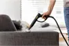 A person is using a steam cleaner on a gray fabric sofa. Náhled obrázku produktu
