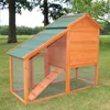 A wooden chicken coop with a green roof and an attached run, set on a grassy lawn with trees in the background. Produktbild-Vorschau