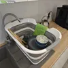 A collapsible sink filled with dishes, a towel, and a kettle, placed in a kitchen sink area. Voir les images du produit