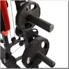 A close-up view of weight plates on a black metal gym equipment frame, with a red padded seat visible in the background. Produktbild-Vorschau