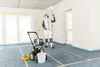 A person is using a paint spraying system in a room under construction. Produktbild-Vorschau