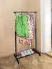 A clothing rack with clothes and shoes on it, placed in a room. Náhled obrázku produktu