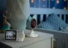 A baby monitor set, including a camera and a receiver, is placed on a nightstand next to a crib in a dimly lit nursery. Náhľad obrázku produktu