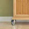 A close-up view of the bottom corner of a wooden cabinet with a caster wheel. Produktbild-Vorschau