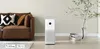 A modern living room with a brown sofa, an air purifier, and decorative items. Produktbild-Vorschau