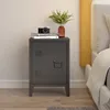 A dark gray metal nightstand with a door and ventilation slots, placed next to a bed. On top of the nightstand are two books and a camera, with a vase of greenery. Náhled obrázku produktu