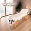 A massage table set up in a room with large windows overlooking the ocean, plants, and candles. Náhled obrázku produktu