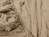 A close-up view of a beige fitted sheet, showing the elasticized edge and fabric texture. Produktbild-Vorschau