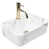 A white marble-patterned sink with a gold faucet, isolated on a white background. Podgląd zdjęcia produktu