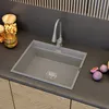 A modern kitchen sink with a gray faucet and a gray sink basin, set against a dark gray backsplash and wooden cabinets. Podgląd zdjęcia produktu
